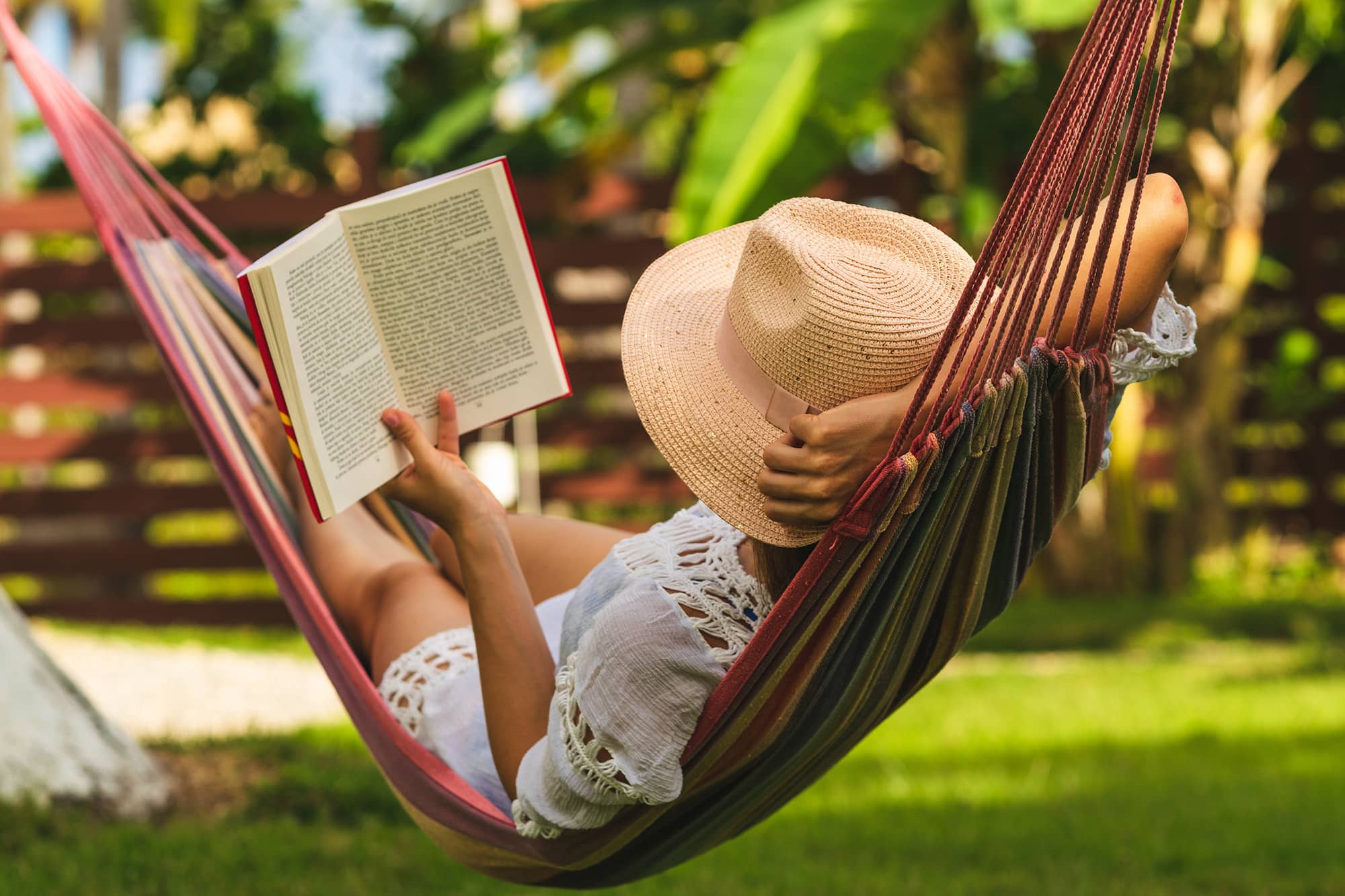 Woman laying in hammock reading a book