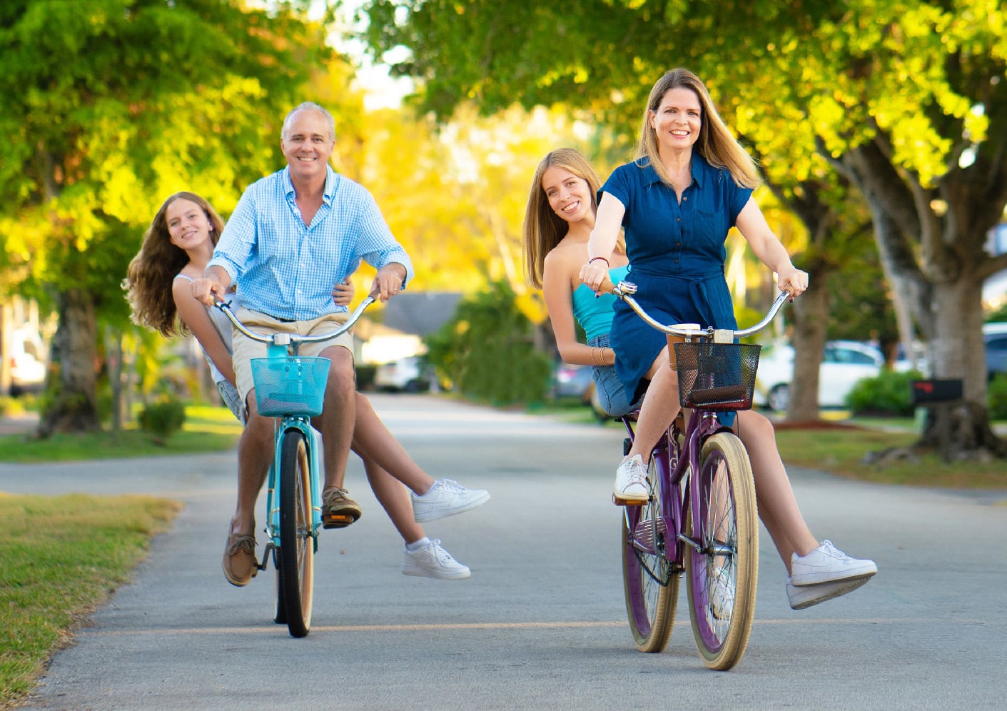Parents riding bikes through neighborhood with teen daughters on the. back