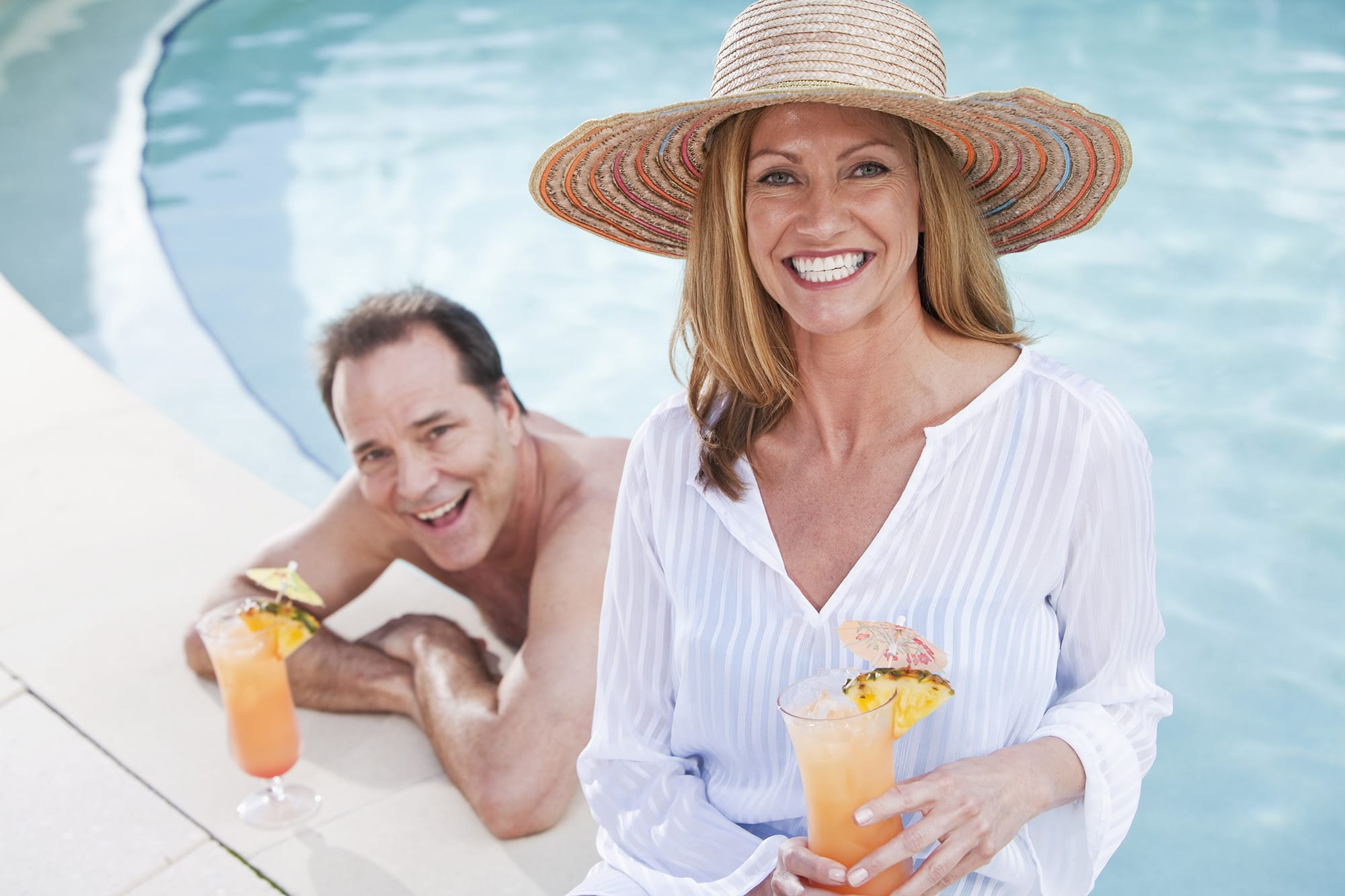 Mature couple at the swimming pool with tropical drinks